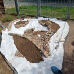 Naturteich im Bau mit Sandboden, Natursteinen und Teichvlies am Rand