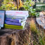 Bücher, Smartphone mit Flora Incognita und Gartenhandschuhe als Werkzeuge für die Gartenplanung