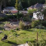 Umgestaltung eines Rasengartens mit neuen geschwungenen Beeten und Natursteinstrukturen